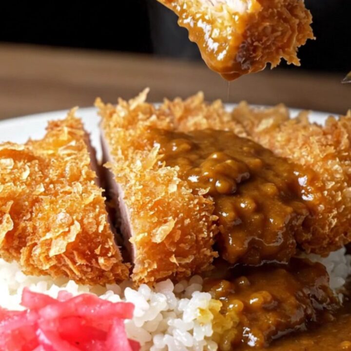 Sliced pork katsu curry over rice with pickled radish