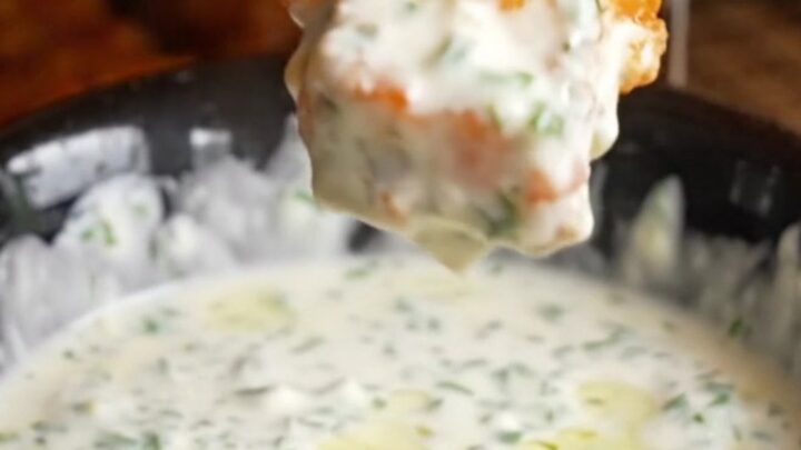 Golden accordion zucchini fries on a platter with a bowl of herb yogurt dip