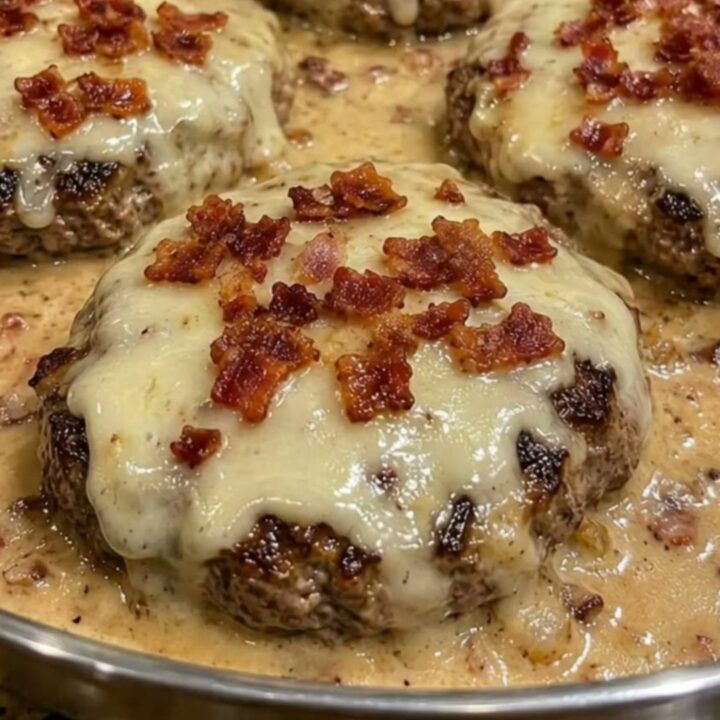 Four juicy bacon Swiss hamburger steaks in a skillet with bubbling creamy gravy.