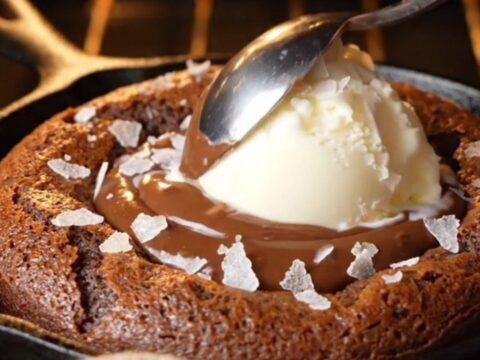 Molten chocolate hazelnut skillet lava cake with vanilla ice cream and sea salt, spoon breaking the center