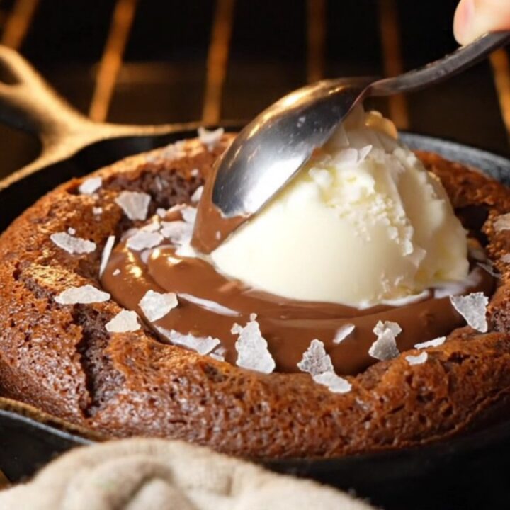 Molten chocolate hazelnut skillet lava cake with vanilla ice cream and sea salt, spoon breaking the center