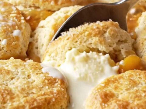 Cast iron skillet with golden buttermilk biscuits over bubbling peach filling