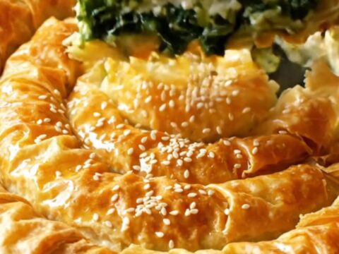 A golden spiral filo pie with spinach and feta filling, sliced to show layers.