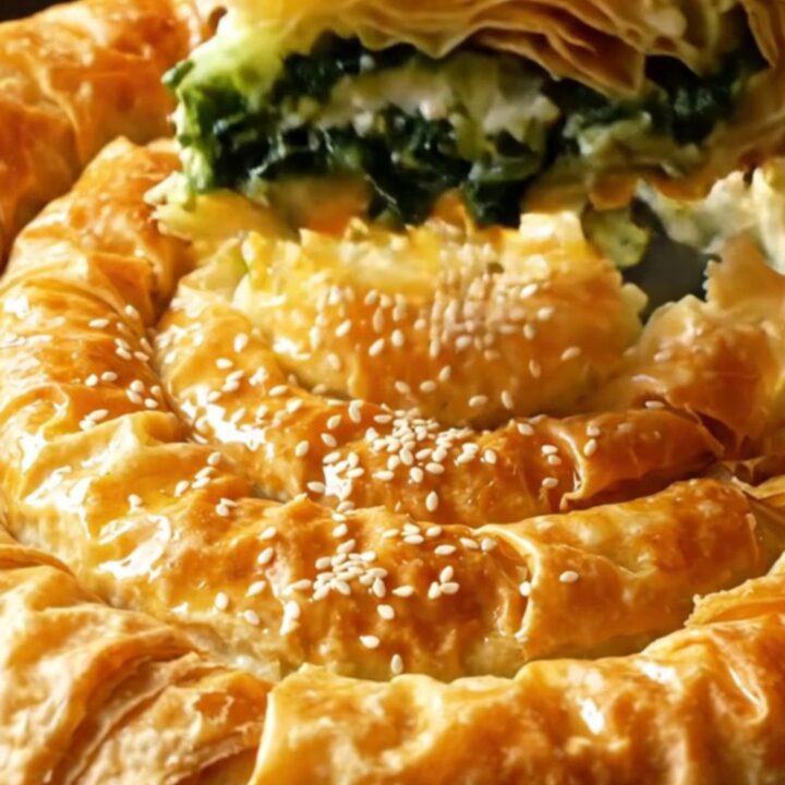 A golden spiral filo pie with spinach and feta filling, sliced to show layers.