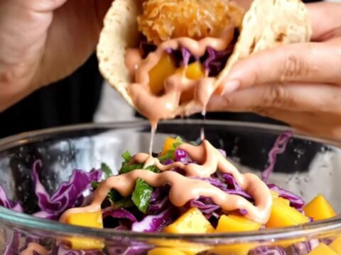 Crispy Baja fish taco with golden beer-battered fish, mango slaw, and chipotle crema on a charred corn tortilla