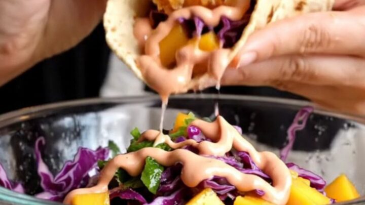 Crispy Baja fish taco with golden beer-battered fish, mango slaw, and chipotle crema on a charred corn tortilla