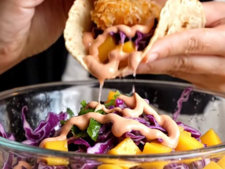 Crispy Baja fish taco with golden beer-battered fish, mango slaw, and chipotle crema on a charred corn tortilla