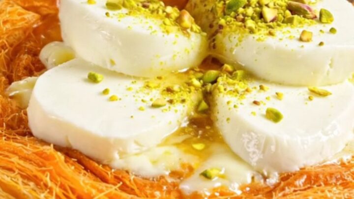 Freshly cooked pistachio kunefe in a copper pan, topped with ground pistachios and a glossy syrup