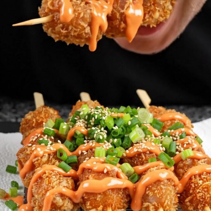 Crispy chicken skewers drizzled with sweet sriracha mayo on a black slate platter