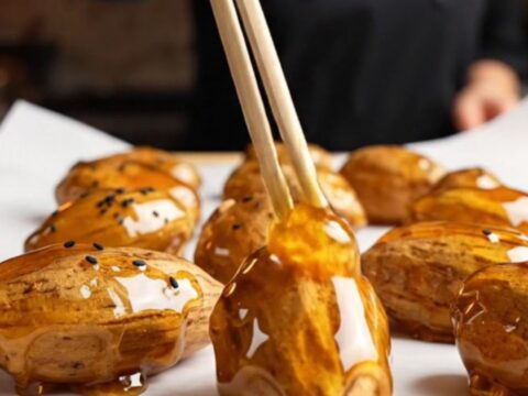 Korean candied sweet potatoes with glossy caramel shell and black sesame seeds on parchment