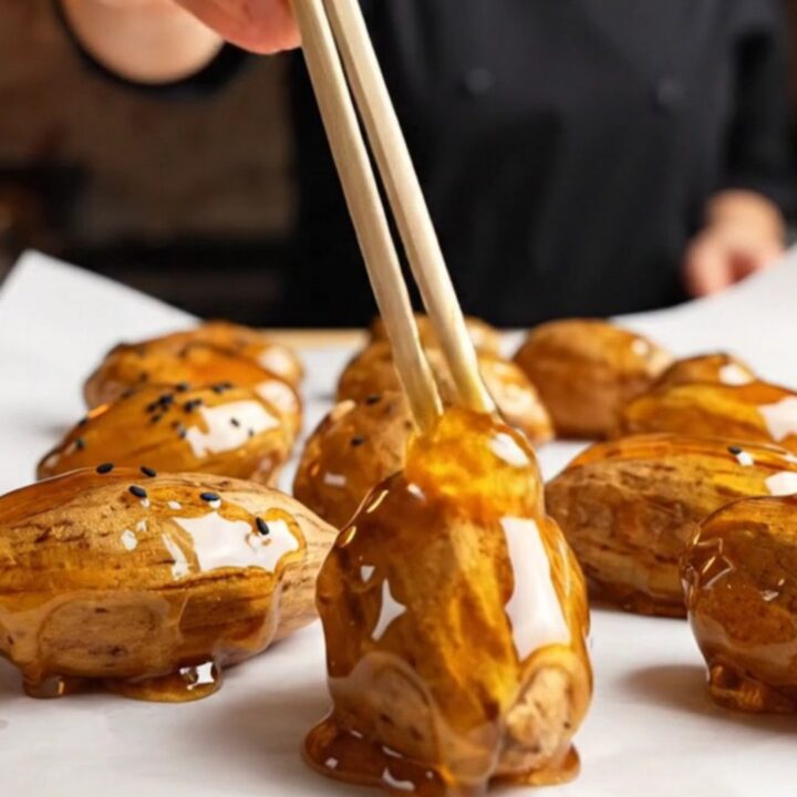 Korean candied sweet potatoes with glossy caramel shell and black sesame seeds on parchment