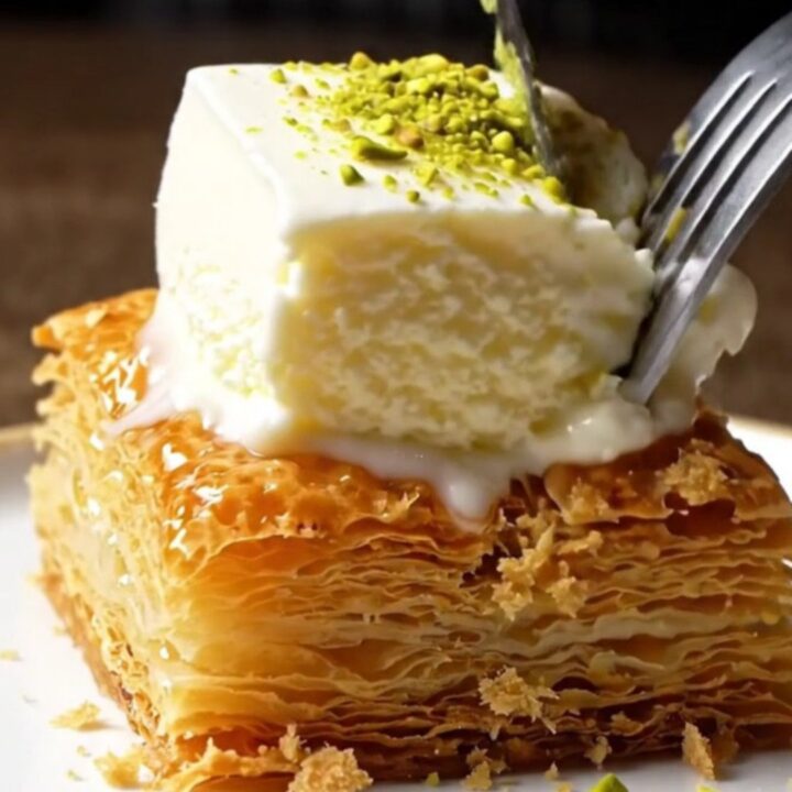 Golden kadayıf topped with a slice of stretchy ice cream and pistachios