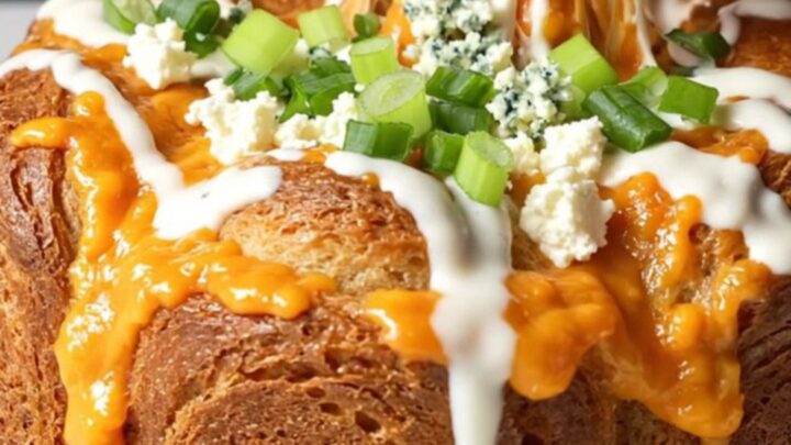 Golden pull-apart monkey bread with melted cheese and buffalo chicken, drizzled with ranch and sprinkled with green onions