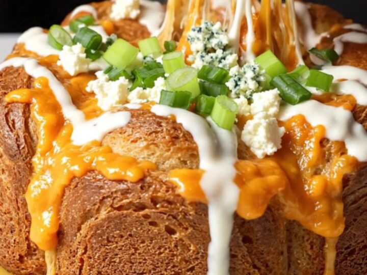 Golden pull-apart monkey bread with melted cheese and buffalo chicken, drizzled with ranch and sprinkled with green onions