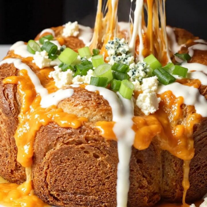 Golden pull-apart monkey bread with melted cheese and buffalo chicken, drizzled with ranch and sprinkled with green onions