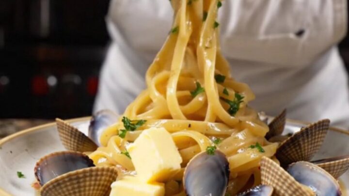 Twirled linguine with clams in a garlic butter white wine sauce, garnished with parsley