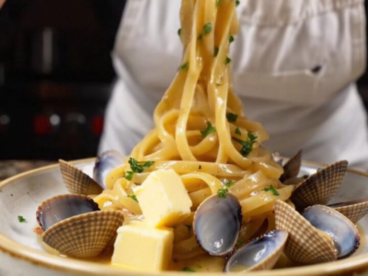 Twirled linguine with clams in a garlic butter white wine sauce, garnished with parsley