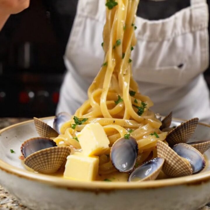 Twirled linguine with clams in a garlic butter white wine sauce, garnished with parsley