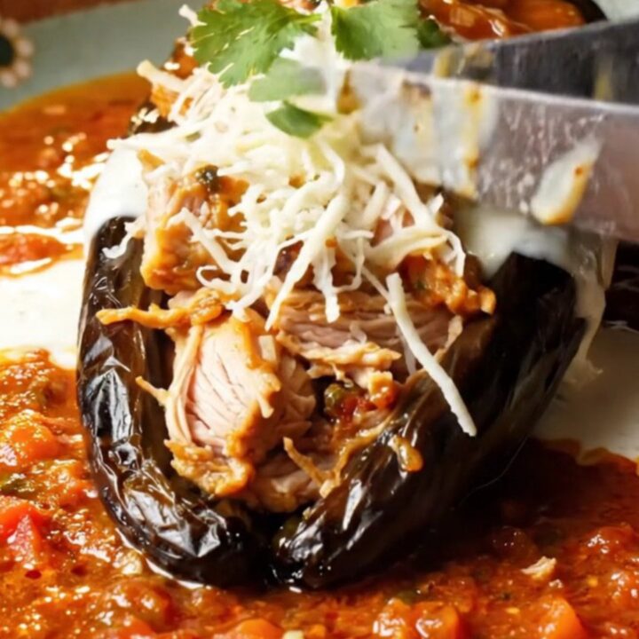 Fire-roasted stuffed poblano chile with melted Queso Oaxaca and charred salsa roja, garnished with crema and cilantro