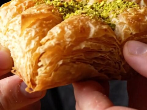 Golden-brown crispy pistachio katmer sliced into triangles, showing layers of filo and green pistachio filling