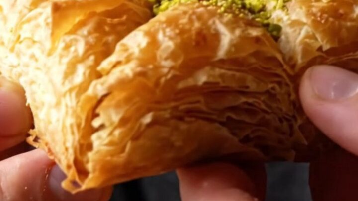 Golden-brown crispy pistachio katmer sliced into triangles, showing layers of filo and green pistachio filling