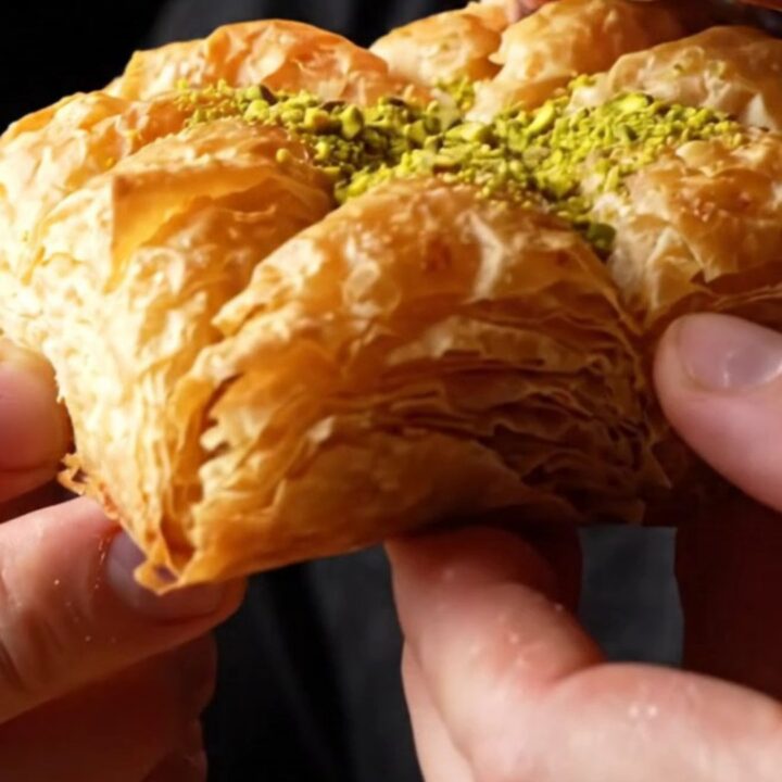 Golden-brown crispy pistachio katmer sliced into triangles, showing layers of filo and green pistachio filling