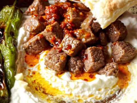 Turkish Ali Nazik Kebab on a terracotta plate, sizzling spiced lamb over smoky eggplant yogurt