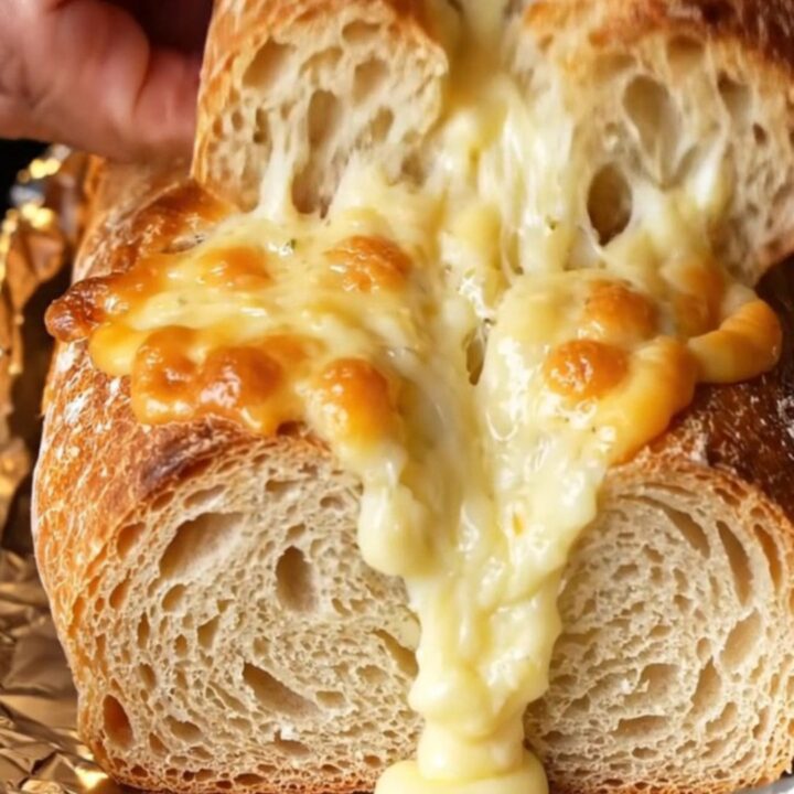 Golden pull-apart bread loaf with melted cheese stretching from a piece being pulled