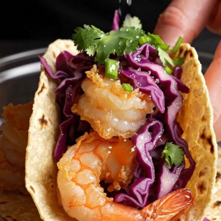 Crispy bang bang shrimp tacos with purple cabbage and lime aioli on a wooden board