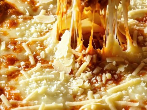 A slice of lasagna bolognese with layers of pasta, meat sauce, and melted cheese on a white plate.