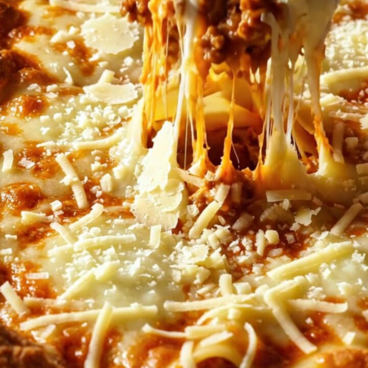A slice of lasagna bolognese with layers of pasta, meat sauce, and melted cheese on a white plate.