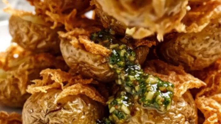 Crispy smashed fingerling potatoes topped with green chimichurri on a rustic platter