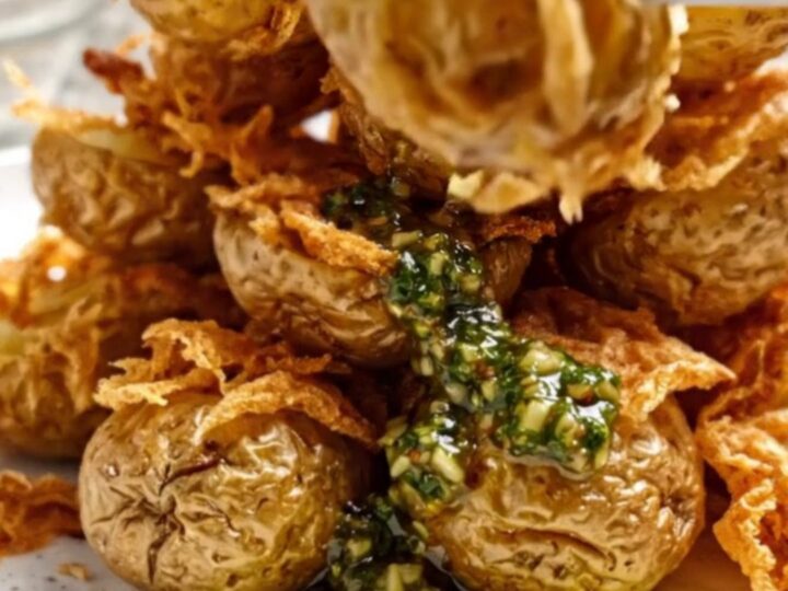 Crispy smashed fingerling potatoes topped with green chimichurri on a rustic platter