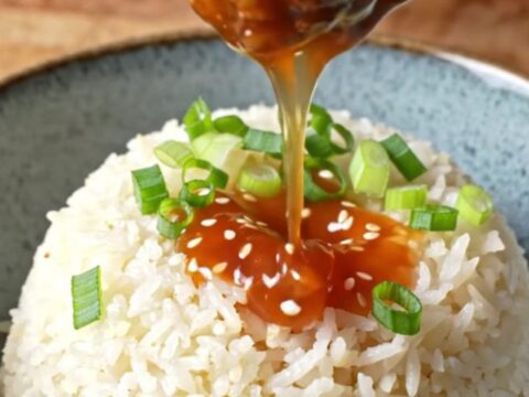 Glossy sweet chili meatballs on a bed of jasmine rice, topped with scallions and sesame seeds.