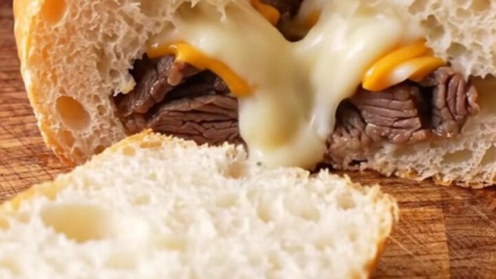 Golden stuffed baguette sliced into thick rounds, showing layers of steak, mushrooms, and melted cheese.