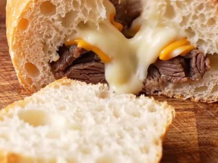 Golden stuffed baguette sliced into thick rounds, showing layers of steak, mushrooms, and melted cheese.