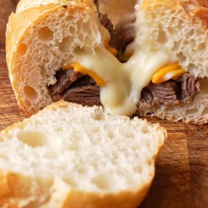 Golden stuffed baguette sliced into thick rounds, showing layers of steak, mushrooms, and melted cheese.