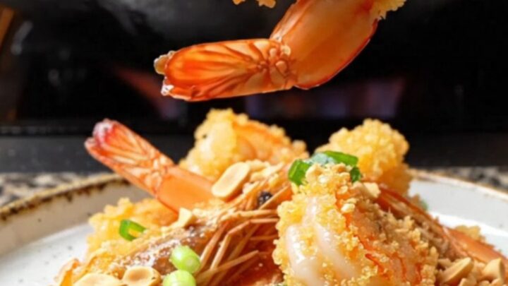 Crispy Szechuan Bang Bang Shrimp on a platter, coated in fiery sauce, topped with crushed peanuts and scallions.