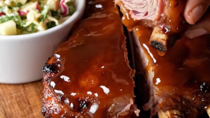Sticky bourbon glazed baby back ribs on a cutting board, sliced between bones, with a glossy caramelized crust.