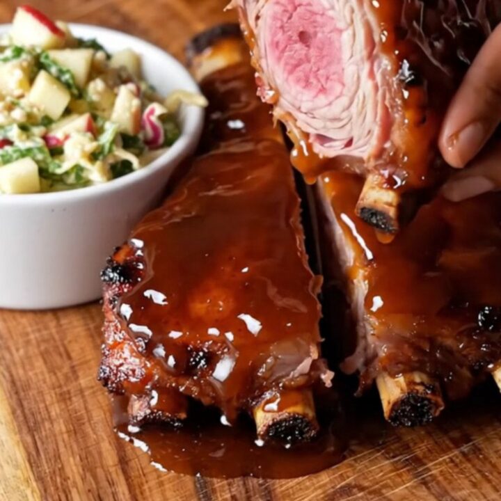 Sticky bourbon glazed baby back ribs on a cutting board, sliced between bones, with a glossy caramelized crust.