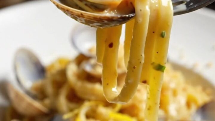 Twirled linguine with clams in a creamy lemon garlic sauce, topped with golden pangrattato.