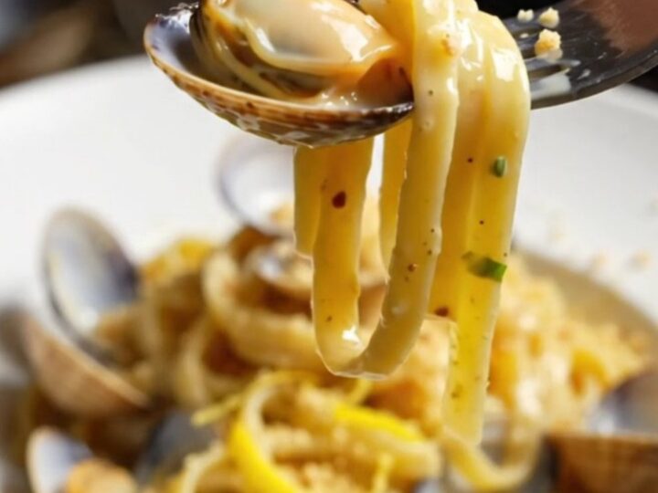 Twirled linguine with clams in a creamy lemon garlic sauce, topped with golden pangrattato.