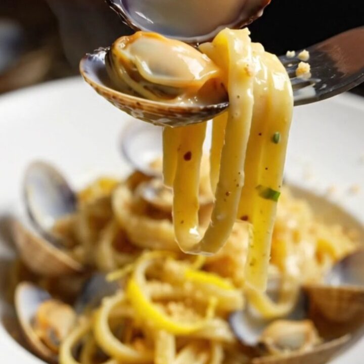 Twirled linguine with clams in a creamy lemon garlic sauce, topped with golden pangrattato.
