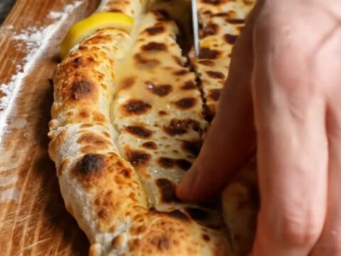 A long, crispy Turkish etli ekmek flatbread with spiced minced meat, baked on a stone