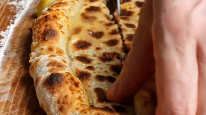 A long, crispy Turkish etli ekmek flatbread with spiced minced meat, baked on a stone
