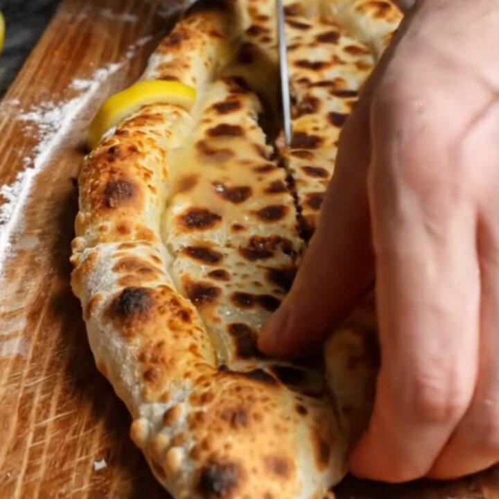 A long, crispy Turkish etli ekmek flatbread with spiced minced meat, baked on a stone