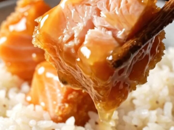 Crispy bang bang salmon bites glazed in a coral sauce, served over coconut rice with green onions and sesame seeds.