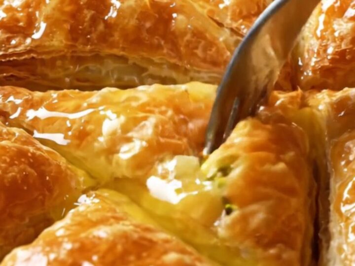 Golden Turkish Şöbiyet baklava triangles with creamy pistachio filling, drizzled with syrup.