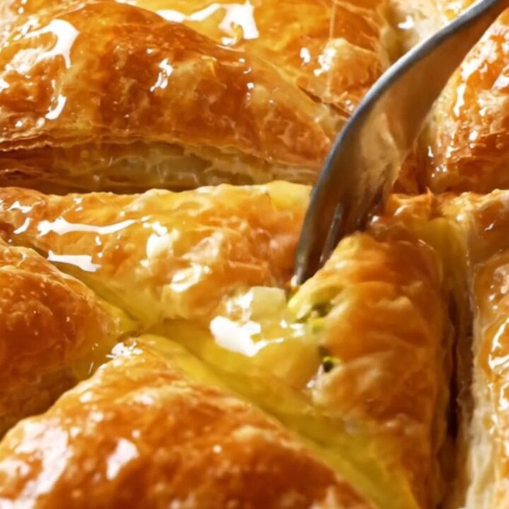 Golden Turkish Şöbiyet baklava triangles with creamy pistachio filling, drizzled with syrup.