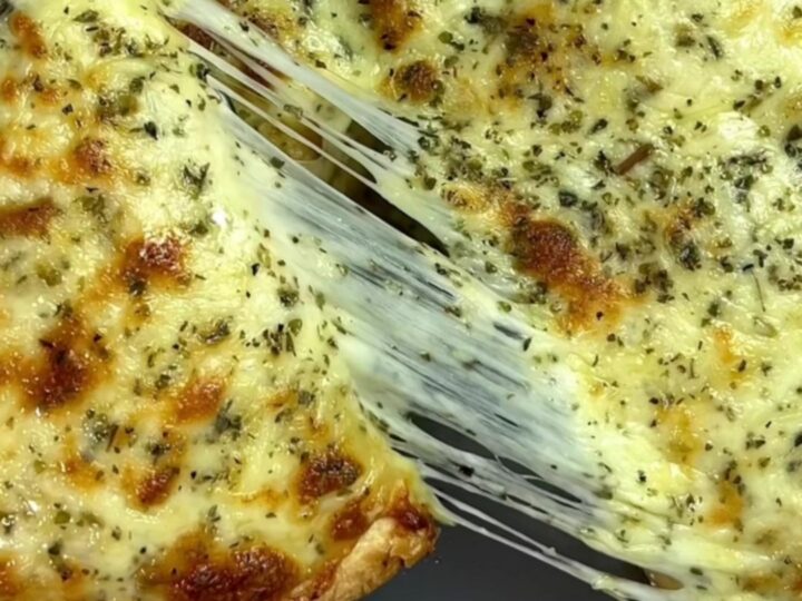 Golden brown tortilla pockets topped with melted mozzarella and fresh parsley, served on a wooden board.